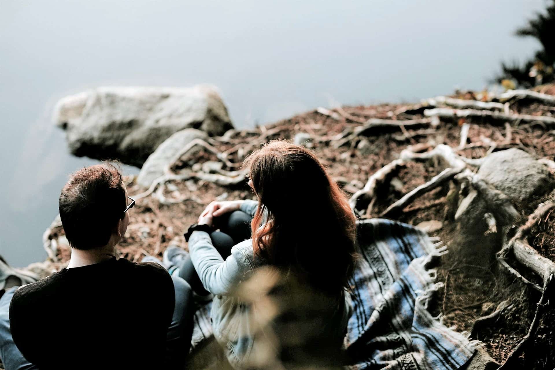 Hur släpper jag taget om en destruktiv relation? Ett par sitter vid en stenig stenstrand och ser ut över vattnet