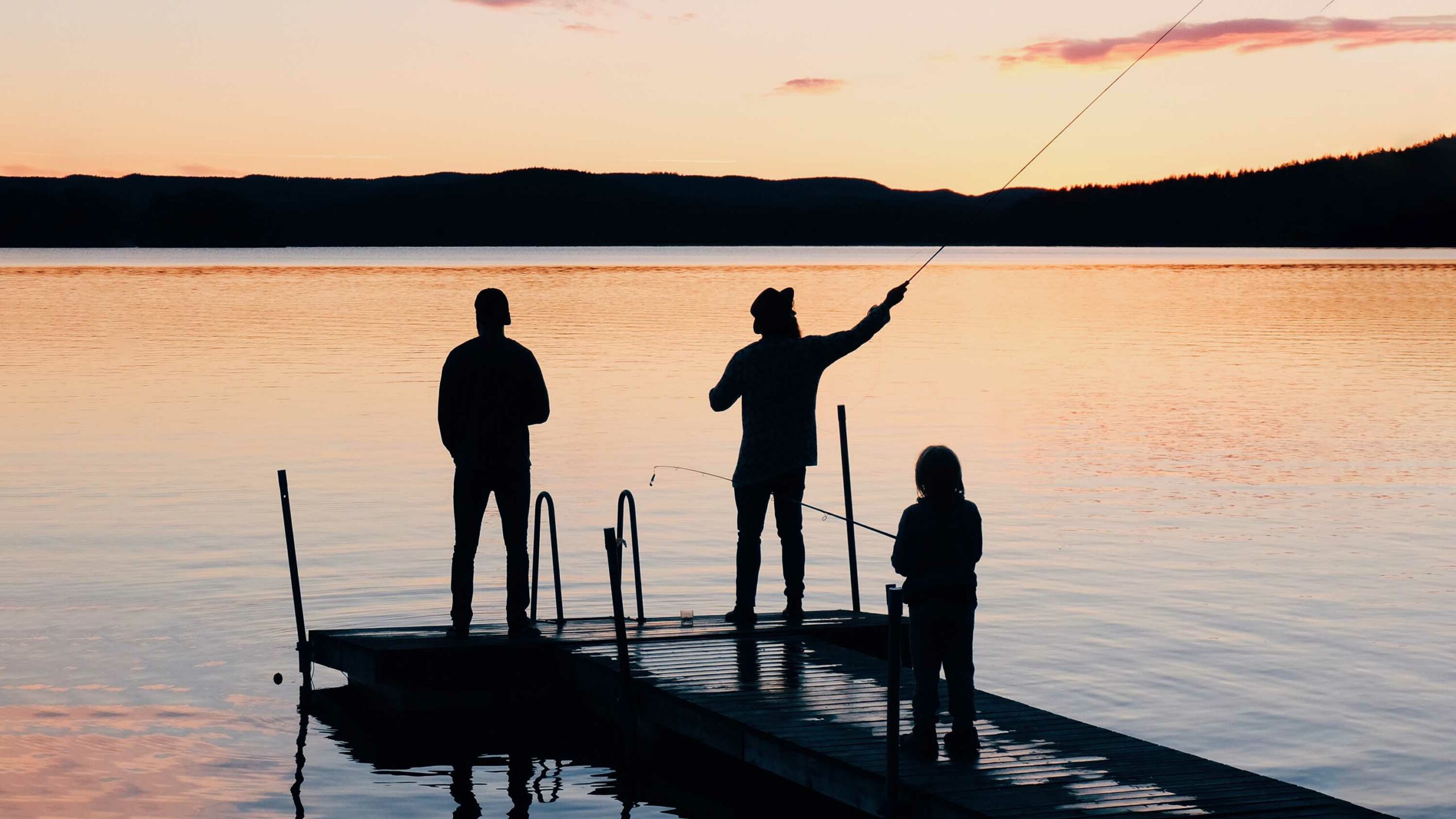 Stressmester-nej tack. Tre personer står på en brygga i solnedgången och fiskar